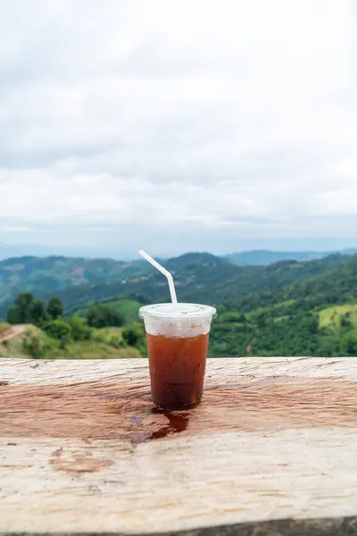 stock image iced americano coffee on wood table with Mountain hill View background