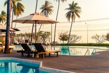 Okyanus geçmişi olan yüzme havuzunun etrafında havuzu olan şemsiyeler - tatil ve tatil kavramı