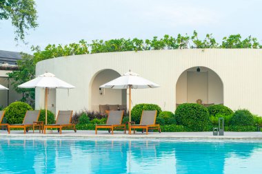 Okyanus geçmişi olan yüzme havuzunun etrafında havuzu olan şemsiyeler - tatil ve tatil kavramı