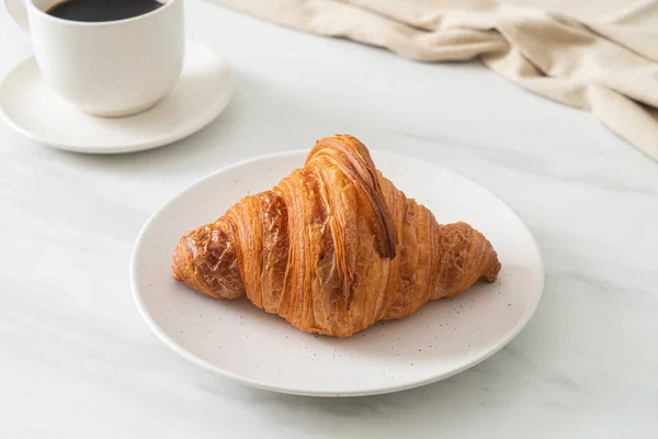 stock image fresh croissant on white plate with black coffee