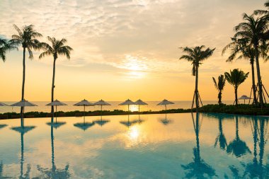 Günbatımında ya da gün doğumunda okyanus arka planında yüzme havuzunun etrafında yüzen şemsiyeli - tatil ve tatil kavramı