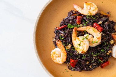 Sarımsaklı ve karidesli kızarmış siyah spagetti.