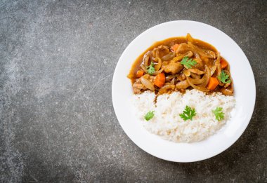 Dilimlenmiş domuz eti, havuç ve soğanlı Japon körili pilavı. Asya usulü.