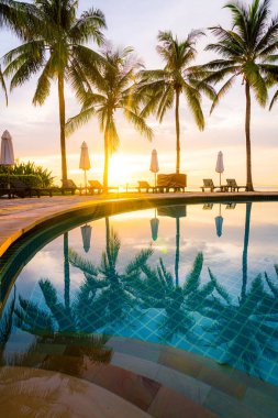 Şemsiye ve sandalye oteldeki yüzme havuzunda sabah gün doğumuyla birlikte - tatil ve tatil konsepti