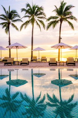 Şemsiye ve sandalye oteldeki yüzme havuzunda sabah gün doğumuyla birlikte - tatil ve tatil konsepti