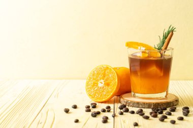 Bir bardak buzlu americano sade kahve ve biberiye ve tarçınla süslenmiş portakal ve limon suyu.
