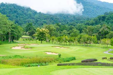 Green and Sand bunkers on Golf course with mountain hill background