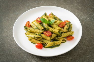 Pesto soslu ve domatesli makarna. Vejetaryen ve vejetaryen yemek tarzı.