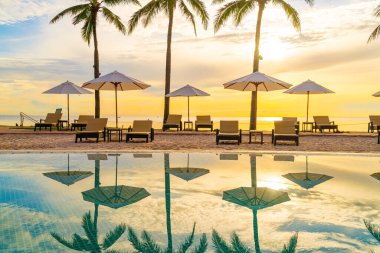Şemsiye ve sandalye tatil ve tatil için dinlenme yeri otelinde yüzme havuzunda günbatımında veya gün doğumunda okyanus kıyısında