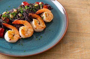 Sarımsaklı ve karidesli kızarmış siyah spagetti.