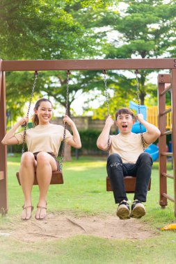 Asian couple love play on the swing in kids playground