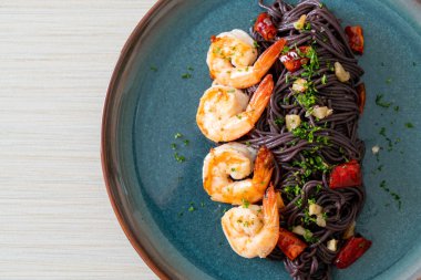Sarımsaklı ve karidesli kızarmış siyah spagetti.