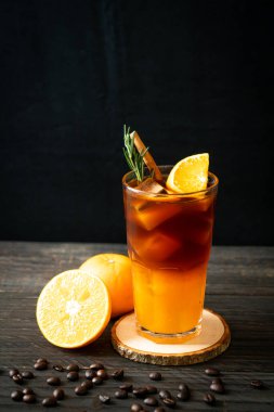 Bir bardak buzlu americano sade kahve ve biberiye ve tarçınla süslenmiş portakal ve limon suyu.