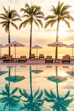 Şemsiye ve sandalye tatil ve tatil için dinlenme yeri otelinde yüzme havuzunda günbatımında veya gün doğumunda okyanus kıyısında