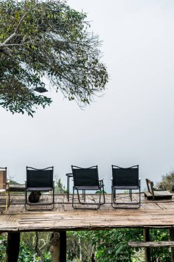 Dağ tepesi ve sisli arka planı olan balkonda boş bir sandalye.