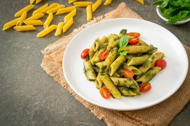 Pesto soslu ve domatesli makarna. Vejetaryen ve vejetaryen yemek tarzı.