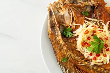 Balık soslu kızarmış deniz levreği balığı ve tabakta baharatlı salata.