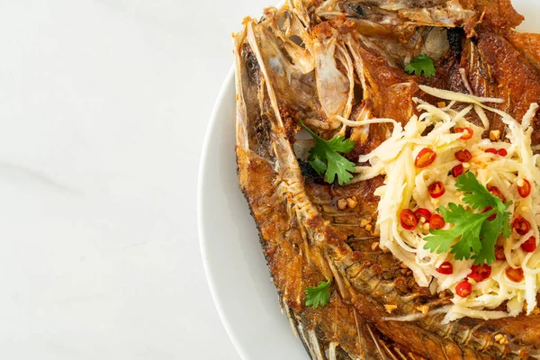 Balık soslu kızarmış deniz levreği balığı ve tabakta baharatlı salata.