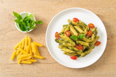 Pesto soslu ve domatesli makarna. Vejetaryen ve vejetaryen yemek tarzı.