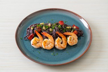 Sarımsaklı ve karidesli kızarmış siyah spagetti.