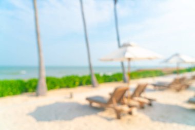 Arka planda plaj sandalyesi ve okyanus denizi olan soyut bulanık şemsiye