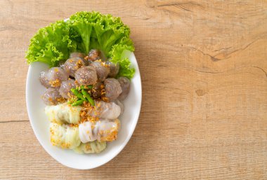 Şeffaf toplara Saku Sai Moo ya da Buharlı Tapioca Köfte Topları ve (Kow Griep Pag Mor) Domuz Buharlı Pirinç Paketleri ya da Haşlanmış Pirinç Kabuklu Mantı denir.