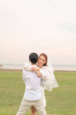 Gelin ve damat kıyafetli mutlu genç Asyalı çift evlenmeye ve evlenmeye hazır.