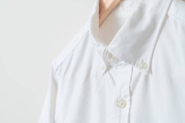 Duvarında ahşap askı olan beyaz gömlek asılı.