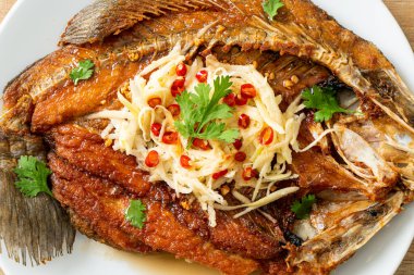 Balık soslu kızarmış deniz levreği balığı ve tabakta baharatlı salata.