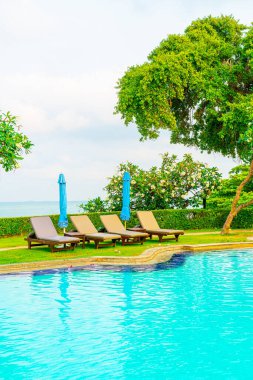 Sandalye havuzu ve şemsiyeyle okyanus arka planında yüzme havuzu