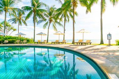 Otelde ve tatil beldesinde yüzme havuzunda güzel şemsiye ve sandalye - tatil kavramı