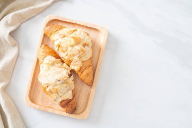 Kremalı kruvasan ve ahşap tabakta badem.