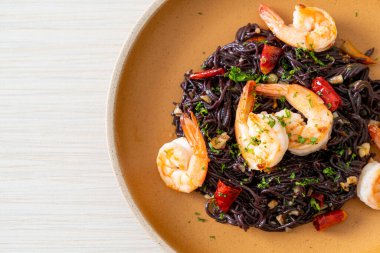 Sarımsaklı ve karidesli kızarmış siyah spagetti.