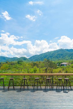 Balkonda boş bir bank ve bar taburesi var.