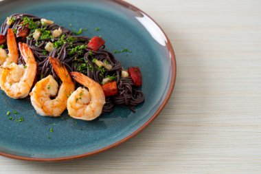 Sarımsaklı ve karidesli kızarmış siyah spagetti.