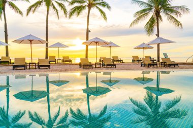 Şemsiye ve sandalye oteldeki yüzme havuzunda sabah gün doğumuyla birlikte - tatil ve tatil konsepti