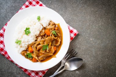 Dilimlenmiş domuz eti, havuç ve soğanlı Japon körili pilavı. Asya usulü.