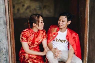 Mutlu genç Asyalı çiftler geleneksel Çin elbiseleriyle sevişir. Kırmızı, geleneksel bayramın ana rengidir. Buna Çin 'de düğün de dahil..