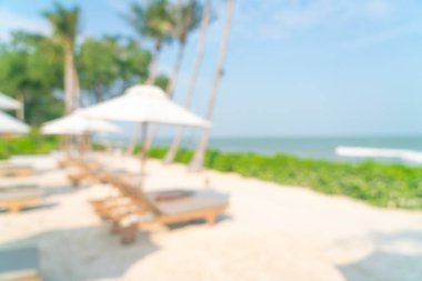 Arka planda plaj sandalyesi ve okyanus denizi olan soyut bulanık şemsiye