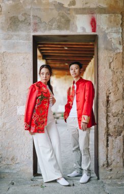 Mutlu genç Asyalı çiftler geleneksel Çin elbiseleriyle sevişir. Kırmızı, geleneksel bayramın ana rengidir. Buna Çin 'de düğün de dahil..
