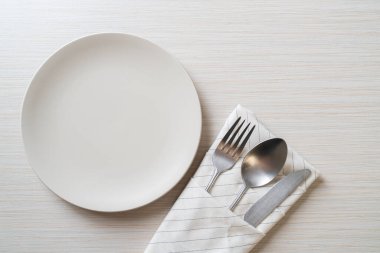 Ahşap zemin üzerinde bıçak, çatal ve kaşık olan boş tabak veya tabak