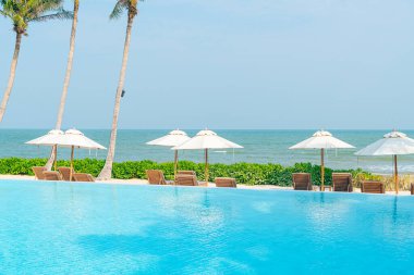Okyanus geçmişi olan yüzme havuzunun etrafında havuzu olan şemsiyeler - tatil ve tatil kavramı