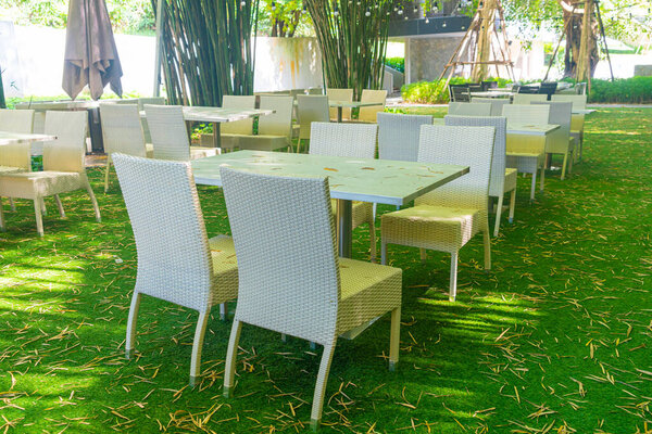empty wicker table and chair in outdoor restaurant with bamboo forest garden