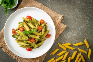 Pesto soslu ve domatesli makarna. Vejetaryen ve vejetaryen yemek tarzı.