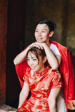 Mutlu genç Asyalı çiftler geleneksel Çin elbiseleriyle sevişir. Kırmızı, geleneksel bayramın ana rengidir. Buna Çin 'de düğün de dahil..