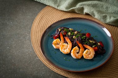 Sarımsaklı ve karidesli kızarmış siyah spagetti.