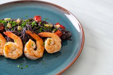 Sarımsaklı ve karidesli kızarmış siyah spagetti.