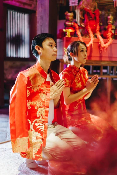 Happy young Asian couple love in Chinese traditional dresses praying at Chinese temple