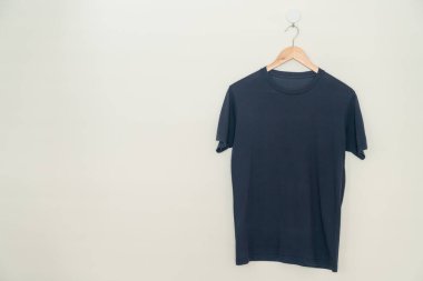 navy t-shirt hanging with wood hanger on wall