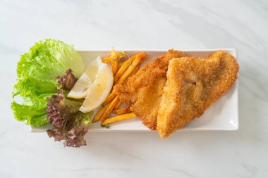 balık ve patates kızartması - kızarmış balık fileto patates cipsi ve limonlu beyaz tabak